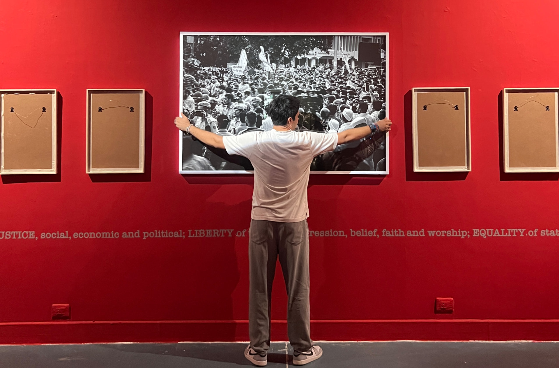 Visitor holding a framed crowd photograph on a red wall
